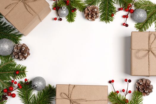 Christmas tree branch with snow , pine cones, red berries and gift boxes on white background with copy space