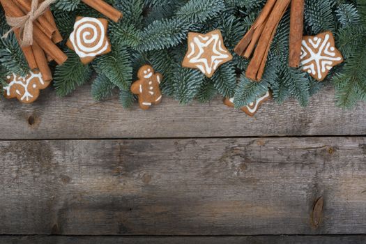 Christmas design boder frame greeting card of noble fir tree branches and gingerbread cookies on wooden background