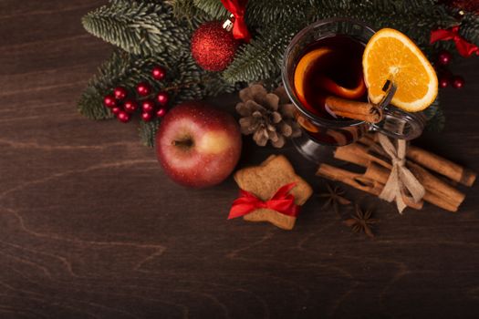 Mulled wine with cinnamon sticks orange fir tree branch and baubles Christmas composition over dark wooden background