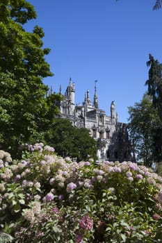 Quinta da Regaleira on  abright sunny day with blooming flowers in front.