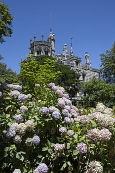 Quinta da Regaleira on a bright sunny day with blooming flowers in front.