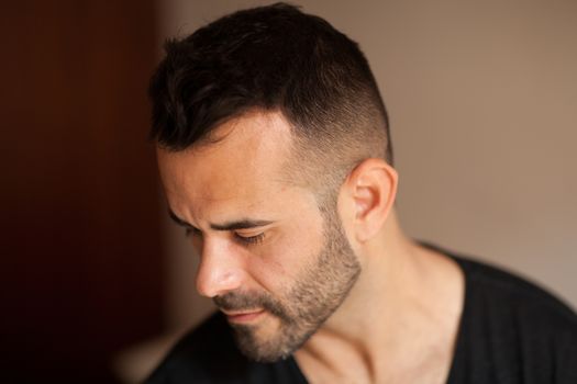 Dark-haired man looking down in soft light