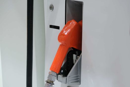 The Fuel pump. Detail of a Orange hand holding a fuel pump at a station