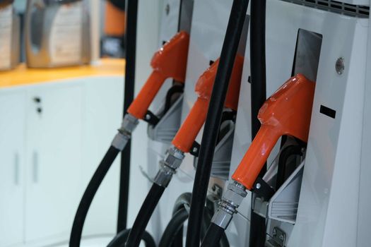 The Fuel pump. Detail of a Orange hand holding a fuel pump at a station