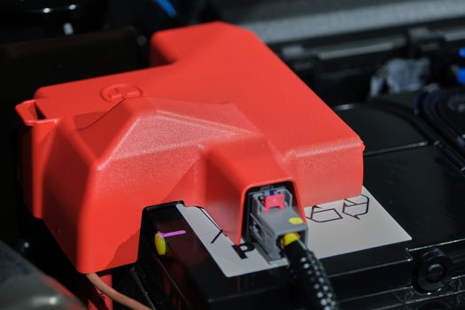 The plastic cover of the positive battery cell tip with the red plus symbol, the battery is placed in the engine compartment.