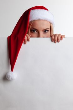 Santa girl hiding behind blank vintage sign billboard. Christmas woman in Santa hat showing paper sign.