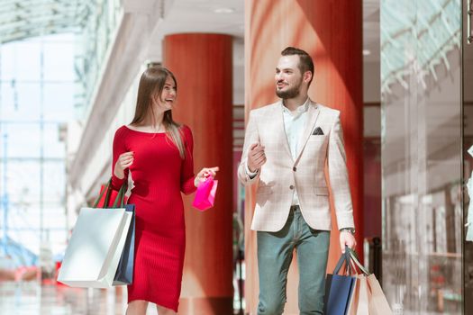 Young elegant couple walking with shopping bags in store