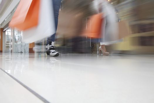 Women walking fast in shopping mall with bags sale rush concept