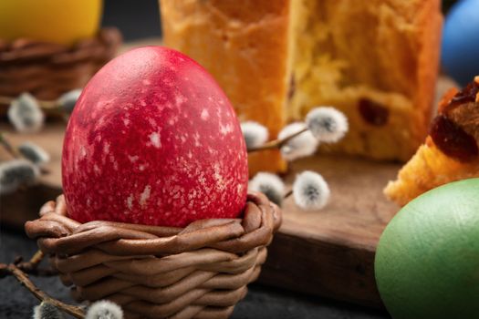 Red Egg in a wicker stand, Easter cake on a cutting board and painted eggs on the table - traditional Easter breakfast.