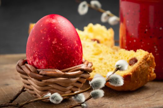 Red Easter egg, a slice of Easter cake and a cup of coffee on a cutting board on a dark table - traditional Easter breakfast.