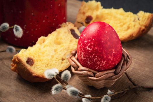 Red Easter egg, a slice of Easter cake and a cup of coffee on a cutting board on a dark table - traditional Easter breakfast.