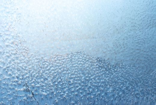 Surface of a winter frozen window is backlit by the sun outside, background, texture.