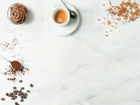 Sweet flat lay background. Chocolate, sugar, hazelnut cocoa spread, cocoa powder and coffee cup on white marble tabletop with copy space. Can use as mock up or special offer for cafe or confectionery