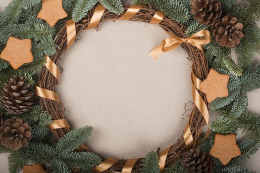 Christmas decorative wreath with noble fir tree twigs pine cones and gingerbread cookies on craft paper background with copy space for text