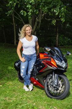 twenty something blond woman, standing beside her sport motocycle