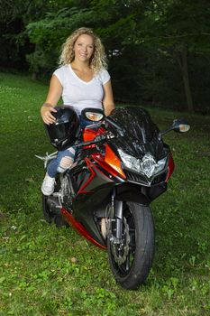 Young woman, with curly blond hair, sitting on a sports motocycle
