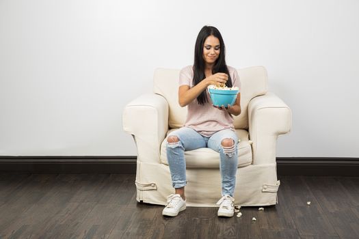 Young woman eating popcorn from a blue bowl