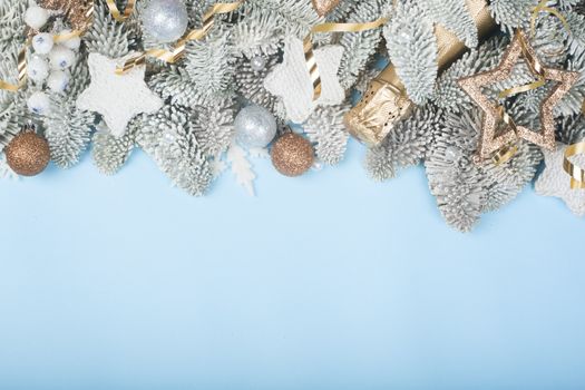 Frosted fir tree twigs and Christmas decorative bauble balls on blue background with copy space for text template flat lay top view design