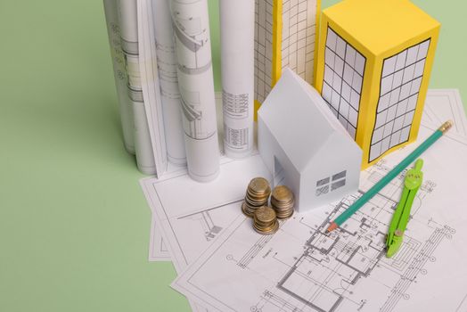 White family paper house, house projects plan and blueprints in the background. Minimalistic and simple concept, style. Horizontal orientation. View from above.