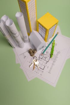 White family paper house, house projects plan and blueprints in the background. Minimalistic and simple concept, style. Horizontal orientation. View from above.