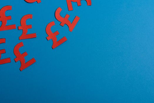 Paper yellow symbols of british pound currency on blue background. View from above with copy space
