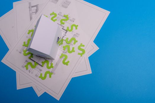 Paper skyscrapers , us dollar money, house projects plan and blueprints on blue background paper. Minimalistic and simple concept, style. Horizontal orientation. View from above. Copy space.