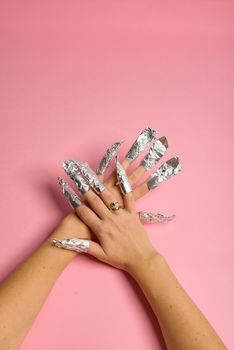 The procedure for removing varnish from nails hybrid nails in progress. Gel nail polish remover foils on woman's hands