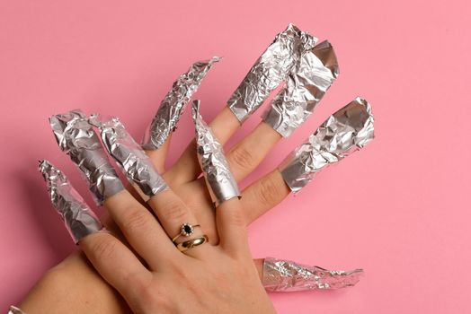 The procedure for removing varnish from nails hybrid nails in progress. Gel nail polish remover foils on woman's hands