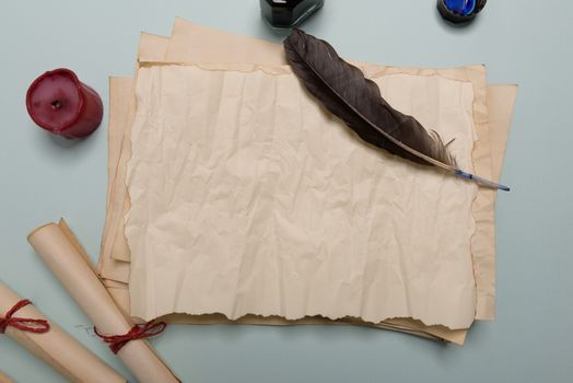 Raven feather, inkwell and old yellowed paper on red background. Copy space. Old letter.