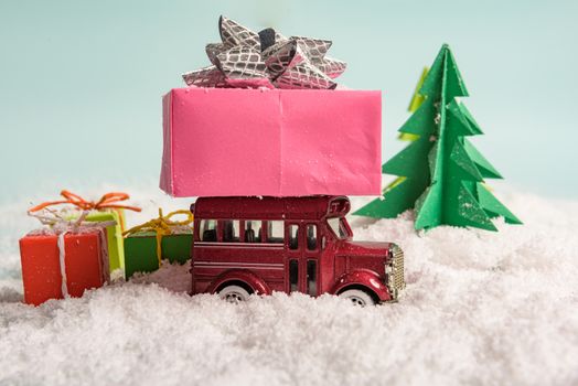 a toy car carries presents under the Christmas tree at snow. view from above. copy space