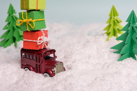 a toy car carries presents under the Christmas tree at snow. view from above. copy space