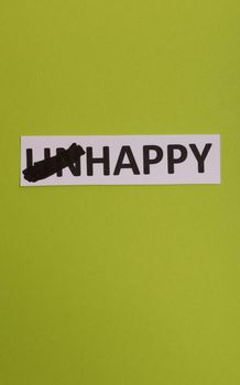 card with text unhappy, cutting word 'un' so it written 'happy'. Copy space. Lime background. Studio shoot.