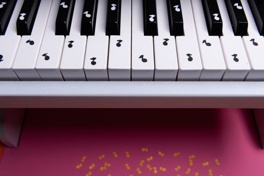 white toy piano with paper notes. music piano concept. view from above. White, black and yellow music notes.