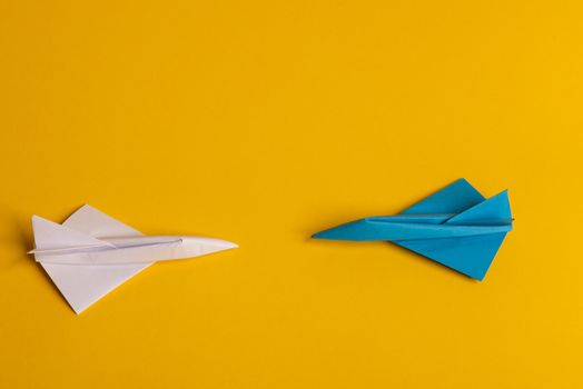 Group of paper plane in one direction and with one individual pointing in the different way on yellow background. Business for innovative solution concept. Dotted line from aircraft tail.