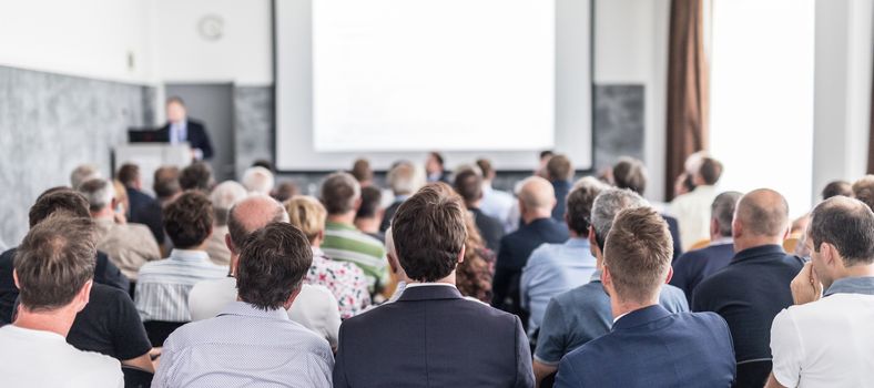 Speaker giving a talk in conference hall at business event. Audience at the conference hall. Business and Entrepreneurship concept. Focus on unrecognizable people in audience.