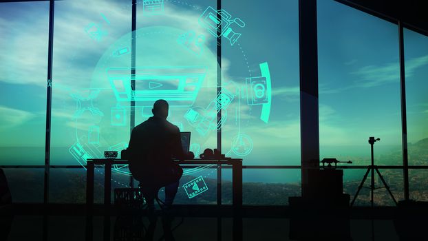 In his cabinet, in a beautiful view of nature, a videographer works while looking at the virtual holographic interface.