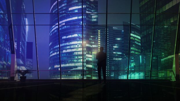 Male silhouette against the background of a business center with evening illumination.