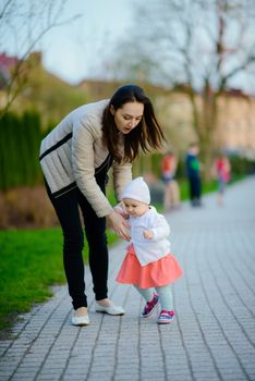 Happy mother and daughter in the park. Beauty nature scene with family outdoor lifestyle. Happy family resting together on the green grass, having fun outdoor. Happiness and harmony in family life.