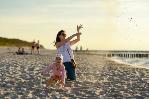 Mother and little daughter walking on the beach.