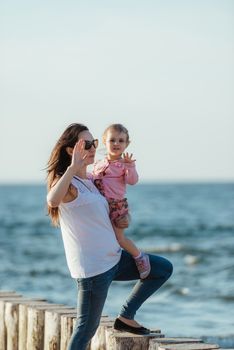 Mother and little daughter walking on the beach.