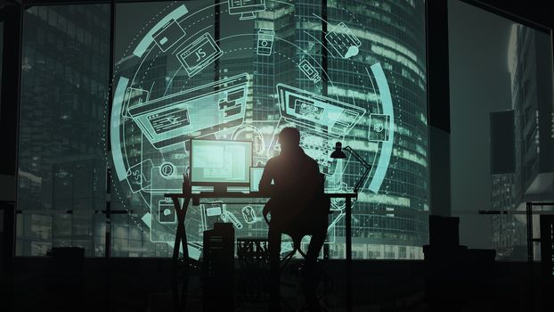 Silhouette of a programmer working in the office against the background of night skyscrapers and virtual infographics.