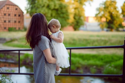 Happy mother and daughter in the park. Beauty nature scene with family outdoor lifestyle. Happy family resting together on the green grass, having fun outdoor. Happiness and harmony in family life.