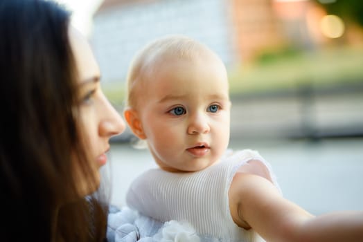 Happy mother and daughter in the park. Beauty nature scene with family outdoor lifestyle. Happy family resting together on the green grass, having fun outdoor. Happiness and harmony in family life.