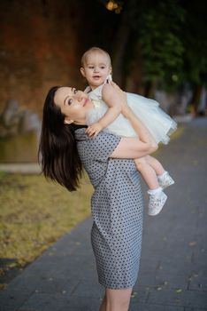 Happy mother and daughter in the park. Beauty nature scene with family outdoor lifestyle. Happy family resting together on the green grass, having fun outdoor. Happiness and harmony in family life.