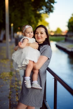 Happy mother and daughter in the park. Beauty nature scene with family outdoor lifestyle. Happy family resting together on the green grass, having fun outdoor. Happiness and harmony in family life.