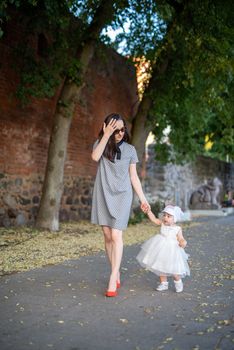 Happy mother and daughter in the park. Beauty nature scene with family outdoor lifestyle. Happy family resting together on the green grass, having fun outdoor. Happiness and harmony in family life.