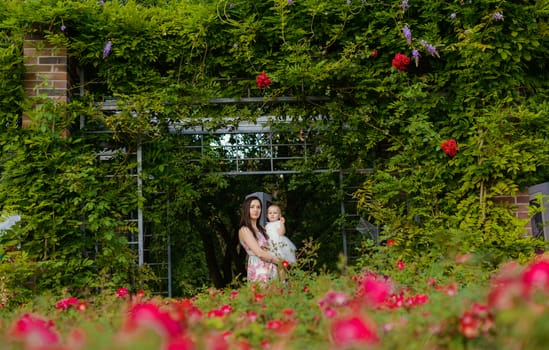 Happy mother and daughter in the park. Beauty nature scene with family outdoor lifestyle. Happy family resting together on the green grass, having fun outdoor. Happiness and harmony in family life.