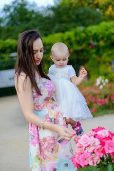 Happy mother and daughter in the park. Beauty nature scene with family outdoor lifestyle. Happy family resting together on the green grass, having fun outdoor. Happiness and harmony in family life.