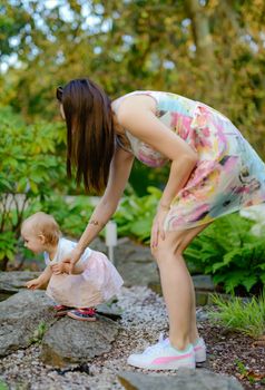 Happy mother and daughter in the park. Beauty nature scene with family outdoor lifestyle. Happy family resting together on the green grass, having fun outdoor. Happiness and harmony in family life.