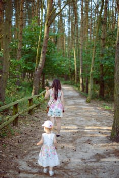 Happy mother and daughter in the park. Beauty nature scene with family outdoor lifestyle. Happy family resting together on the green grass, having fun outdoor. Happiness and harmony in family life.